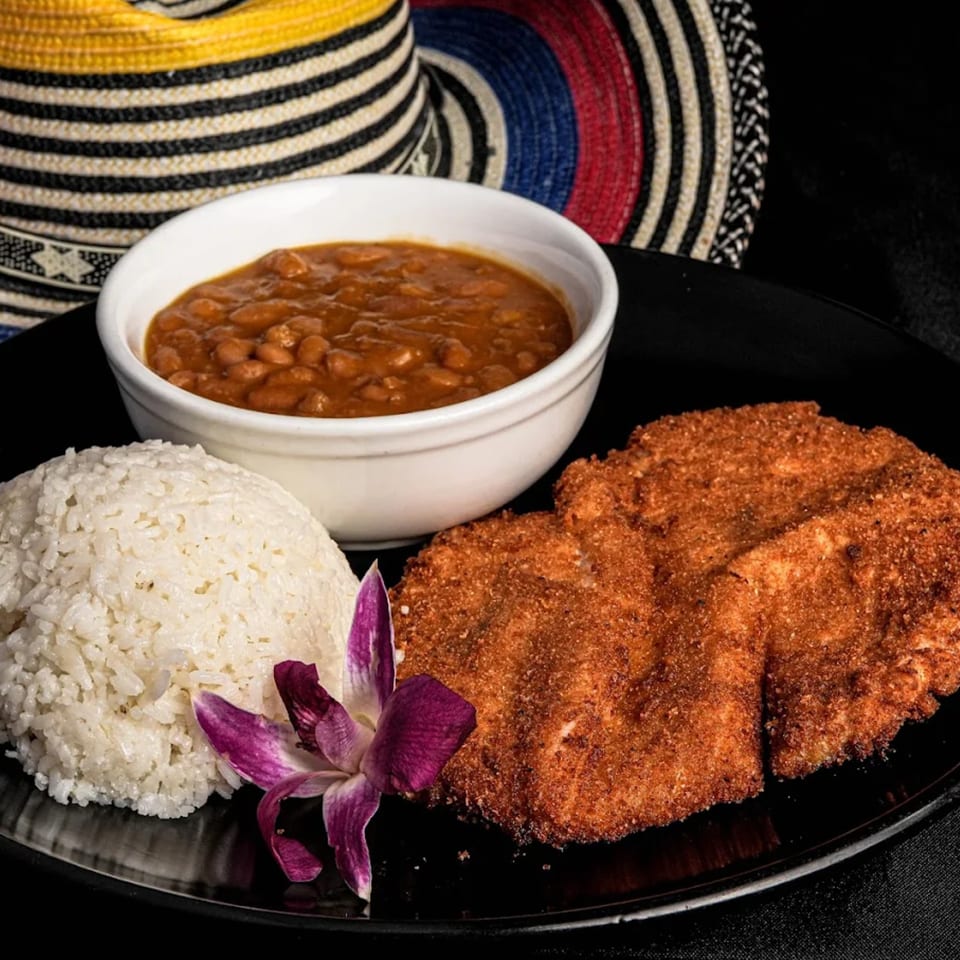 Mendoza's Colombian Cafe's breaded pork loin with rice, beans, and an orchid garnish.