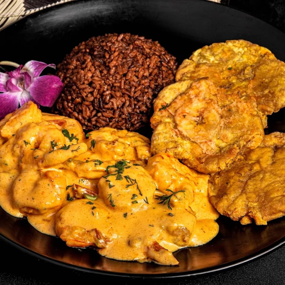 Colombian shrimp in creamy sauce with red rice, fried plantains, and a purple orchid.